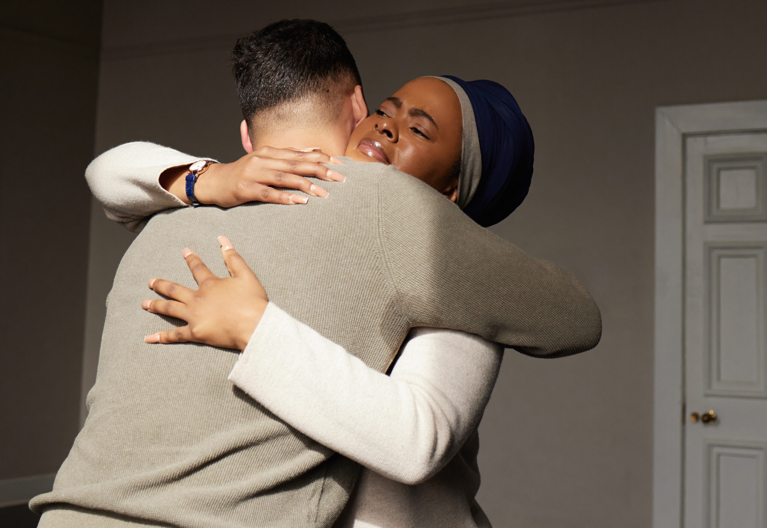 Hug, support and woman embrace a man for comfort, grief and care after bad news or problems in a home or house. Cancer, sad and depression by people hugging for empathy, love and hope together.